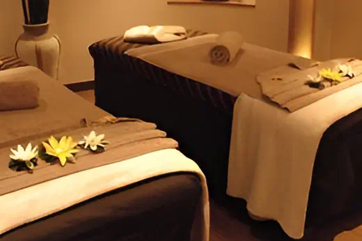 Peaceful massage treatment room with warm lighting and neatly arranged towels at DLUX Health & Beauty Centre