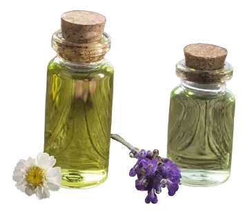 Two glass bottles of essential oils with daisy and lavender flowers placed beside them.